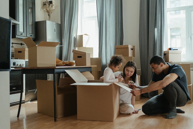 Photo of a family packing for a move and playing with moving boxes as a featured image for post about tips for a smooth move